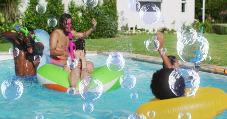Image of bubbles over happy diverse friends having fun in swimming pool. Holidays, vacations and...