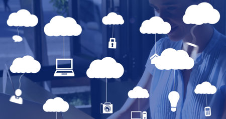 Image of clouds with icons over caucasian woman using laptop. Global business and digital interface...
