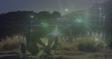Image of glowing network of connections over african american fit man tying shoe laces outdoors. Sports and fitness technology conceptの写真素材