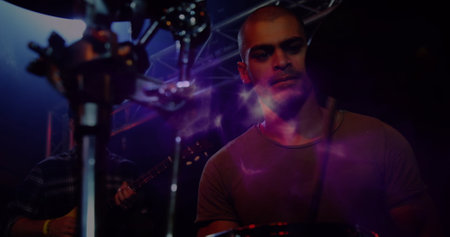 Image of light flares over male drummer playing electronic drum kit. Live music, creativity, performance and entertainment concept digitally generated image.の写真素材