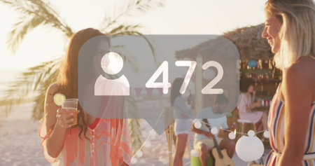 Image of profile icons with increasing numbers over two diverse female friends talking at beach. Social media networking technology conceptの写真素材