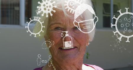 Image of covid cells moving over woman in face mask. Global covid pandemic and healthcare services concept digitally generated image.の写真素材