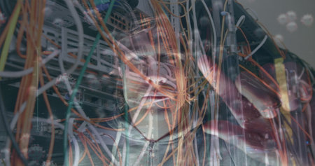 Viewing cables IT technician in zip-up jacket testing switches in server room with LED indicators. Technology, infrastructure, connectivity, digital, industry, engineering, hardwareの写真素材