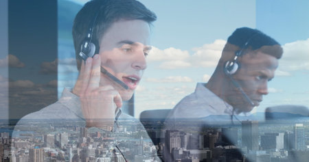 Operating monitors, two call center agents wearing business shirts in office at desks with headsets....