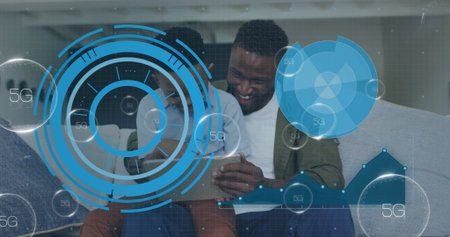 Smiling father and son exploring superimposed 5G data overlays on home sofa, with tablet computer. Family, technology, innovation, connectivity, casual, modern, relaxationの写真素材