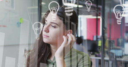 Gazing woman wearing green shirt brushing hair at office with monitor overlays and red panels. Professional, modern, minimalist, innovation, collaboration, workspace, creativeの写真素材