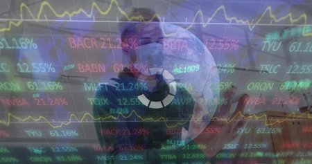 Holding smartphone worker wearing scrubs cap mask in hospital corridor, stock ticker overlays....