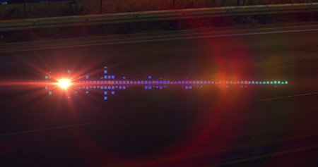 Vehicle headlight producing lens flare with colored reflections on road at night, with guardrail. Night, highway, illumination, abstract, futuristic, moody, scenicの写真素材