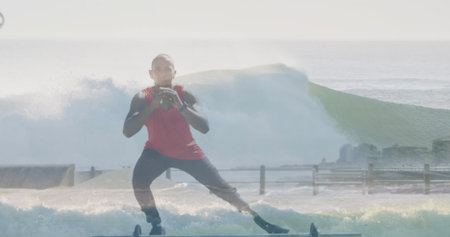Man wearing red top and waterproof shoes balancing on floating board at ocean edge, with railing....