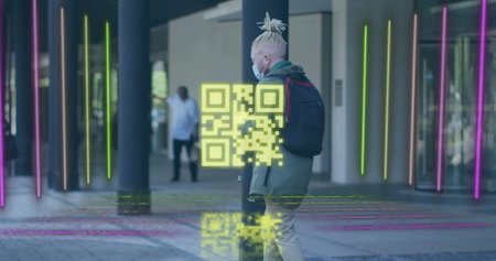 Walking man wearing mask and olive hoodie holding smartphone on covered walkway, displaying QR code....