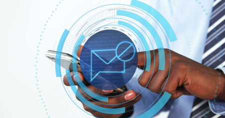 Interacting man in blue shirt checking smartphone in studio, with data overlay and envelope icon. Technology, communication, digital, professional, modern, analytics, innovationの写真素材
