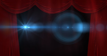 Revealing stage opening under blue spotlight with lens flare at theater, red velvet curtains. Theater, stage, velvet, spotlight, dramatic, performance, interiorの写真素材