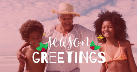 Smiling senior woman wearing straw sun hat hugging grandchildren on sandy beach, with greeting text. Family, celebration, leisure, outdoor, scenic, joyful, lifestyleの写真素材