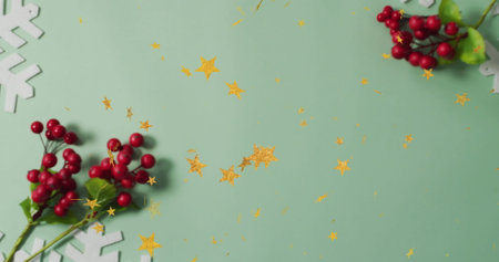 Featuring red berry sprigs on mint table, scattering snowflakes and gold star confetti, copy space. Festive, holiday, celebration, seasonal, craft, decor, elegantの写真素材