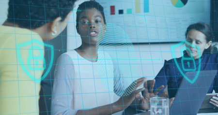Showing African American woman pointing at tablet on conference table, holographic security icons....