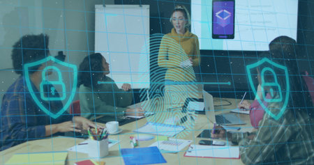 Presenting woman in mustard-yellow hoodie explaining cybersecurity in conference room with laptops....