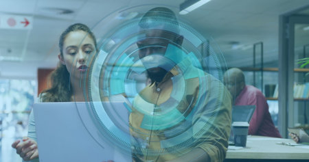 Examining team collaborating on silver laptop screen in modern office, featuring interface graphic. Cooperation, brainstorming, innovation, teamwork, digital, professional, contemporaryの写真素材