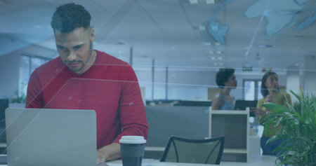 Typing employee in red long-sleeve shirt working on silver laptop at white office desk, coffee cup....