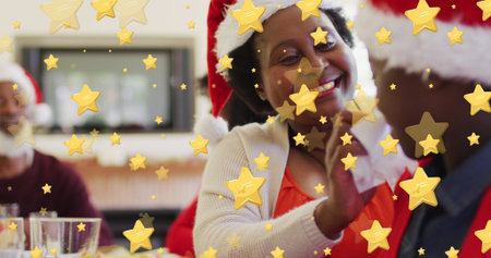 Smiling family wearing Santa hats high-fiving around dining table at home, with star overlays....