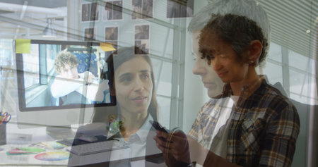 Showing plaid-clad woman holding smartphone at office desk with monitor sticky notes, copy space. Workstation, collaboration, modern, minimalist, technology, business, communicationの写真素材