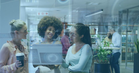 Collaborating trio of women analyzing holographic laptop interface in coworking space, coffee cup. Innovative, teamwork, modernity, brainstorming, networking, professional, creativeの写真素材