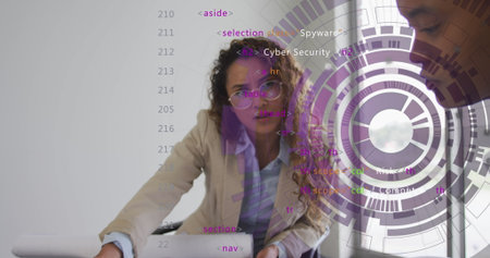 Woman wearing blazer leaning on office table pointing at laptop showing code and circular graphics. Technology, innovation, teamwork, modernity, digital, security, professionalの写真素材