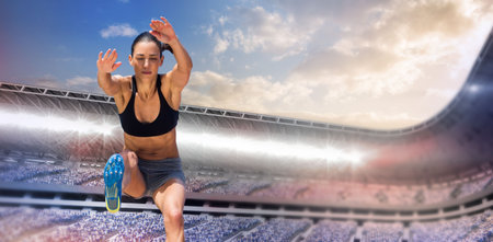 Low angle view of focused female athlete long jumping against sky in stadium