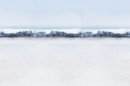 Flat design showing rocky breakwater stretching across pale sandy beach with waves gently breaking. Seascape, coastal, minimalism, tranquility, nature, outdoors, serenityの写真素材