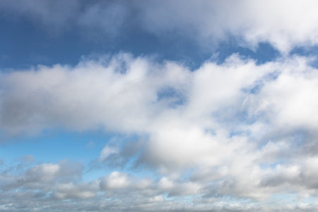 Layered cumulus and stratocumulus clouds are floating across flat design blue sky illustration....