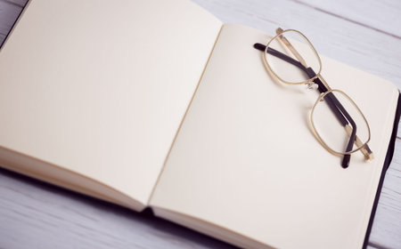 High angle view of book with eyeglasses on wooden tableの写真素材