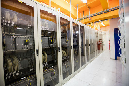 Flat design cabinets are lining data center corridor, showing patch cables, trays, tiles, lights....