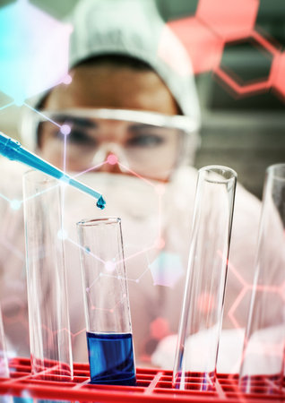 Scientist dropping the reagent into test tube for reaction testing in chemical laboratoryの写真素材
