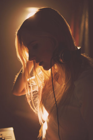 Side view of young woman wearing headphones while standing in music studio