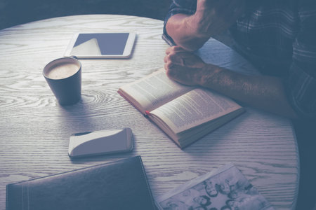 High angle midsection of man reading book at table in house