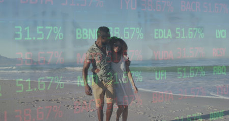 Strolling couple wearing white dress and patterned shirt along sandy beach shore, with ocean waves....
