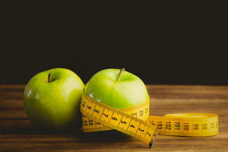 Green apples and measuring tape on wooden table