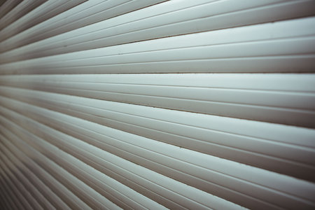Metal rolling shutter door is filling frame in flat design with light grey horizontal slats....