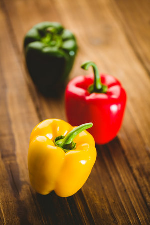 Close-up of multi colored bell peppers on wooden floorの写真素材