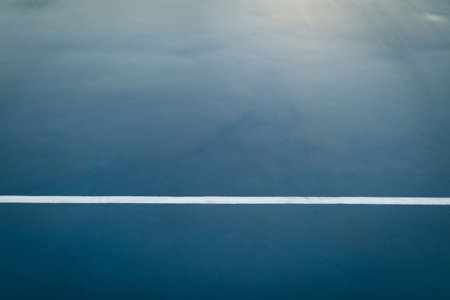 white boundary line stretching horizontally across textured blue sports court in flat design. Athletic, recreation, fitness, minimalism, outdoor, athleticism, sportの写真素材