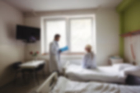 Blurry view of doctor talking to patient in hospital roomの写真素材