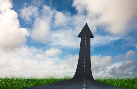 Arrow road with cloudy sky on grassy field