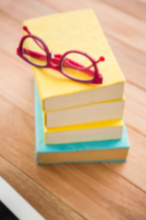 Eyeglasses on stack of books on tableの写真素材