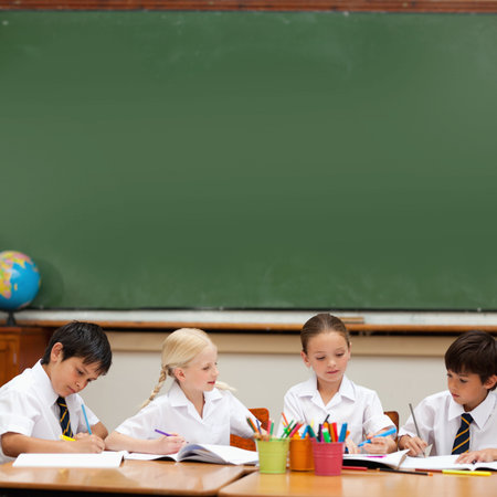Cute pupils sitting at deskの写真素材