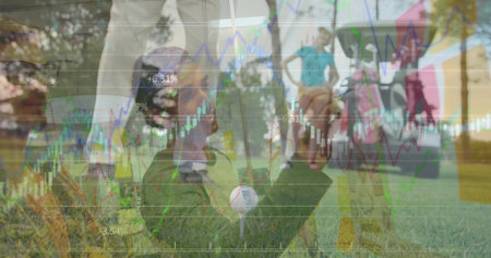 Kneeling man placing golf ball on tee on sunlit fairway, with golf cart and financial charts. Recreation, finance, investment, leisure, outdoor, strategy, analysisの写真素材