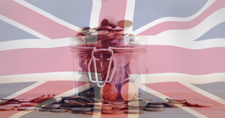 Displaying glass jar holding assorted coins on wooden tabletop, with Union Jack flag overlay. Vintage, finance, savings, currency, collection, patriotic, rusticの写真素材