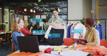 Presenting designer holding two-tone dress on hanger in open-plan workspace, with social icons. Creative, teamwork, fashion, innovative, contemporary, collaborative, aestheticの写真素材