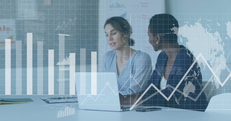 Reviewing laptop data, two women in business attire collaborating in conference area, with binder. Corporate, teamwork, analytics, modern, business, data visualization, professionalの写真素材