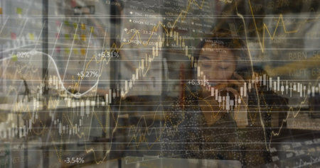 Holding smartphone woman in polka-dot blouse reviewing laptop at office desk, with floating charts....
