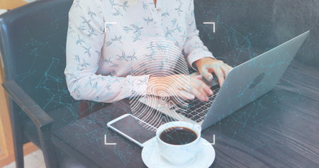 Woman wearing blue bird blouse typing on silver laptop in coffee shop, with fingerprint overlay. Remote work, coworking, digital connectivity, casual professional, modern workspace, concentration, freelancerの写真素材