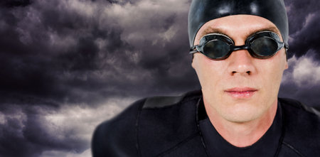 Close-up of male swimmer against digitally generated cloudy skyの写真素材